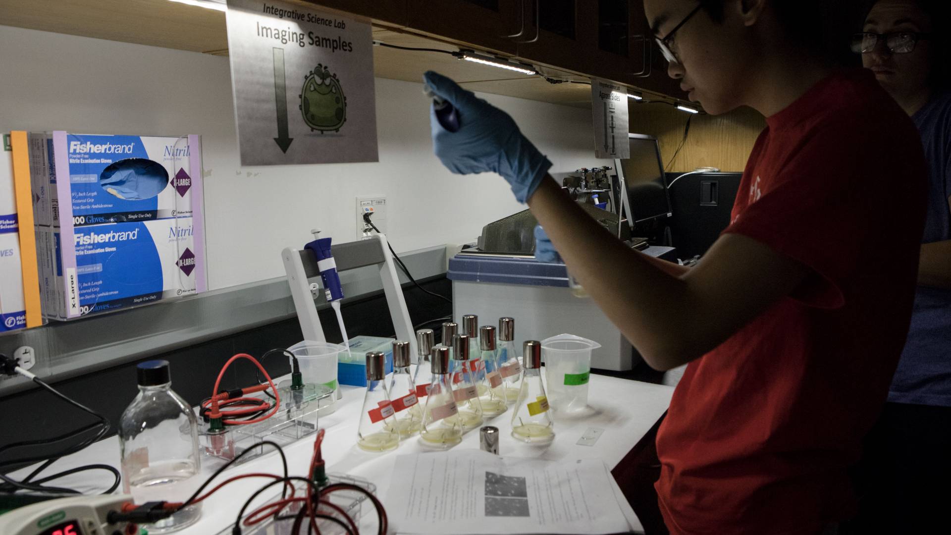 Student putting liquid into tube in lab