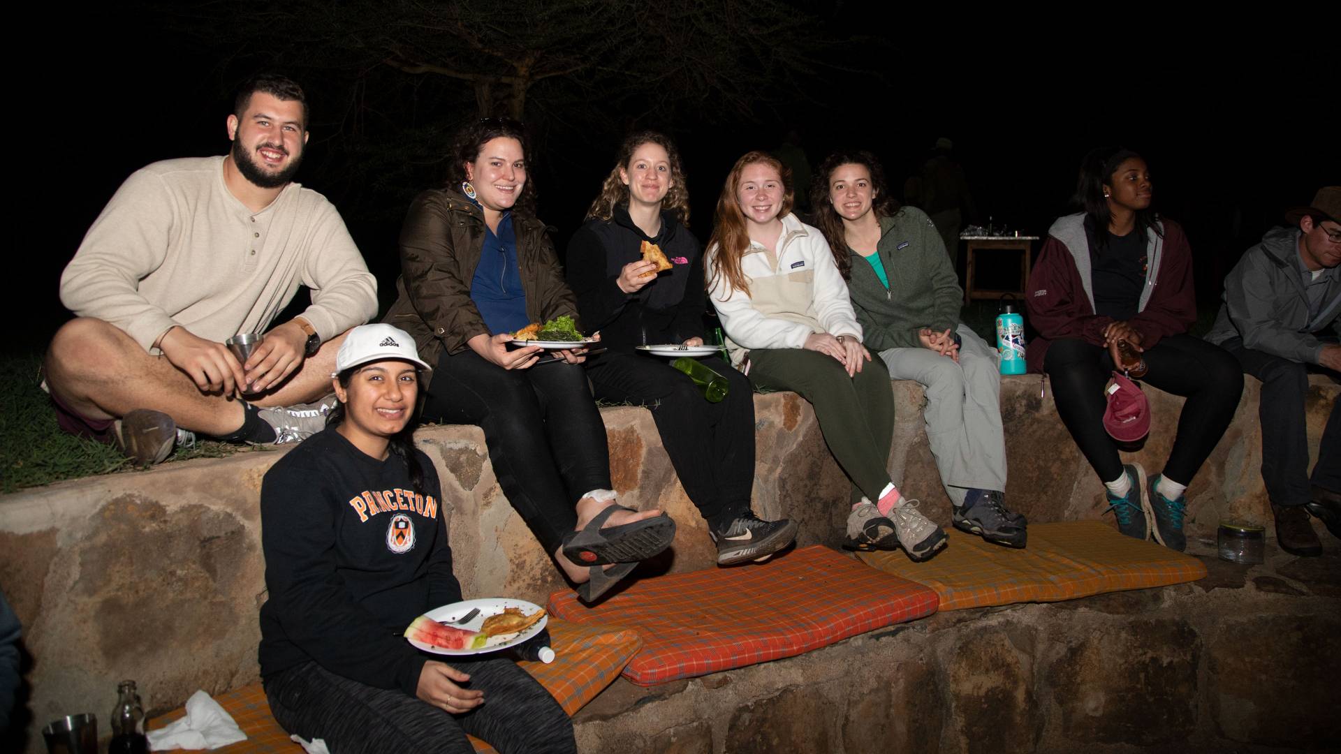 Students sitting around a campfire at night at Mpala