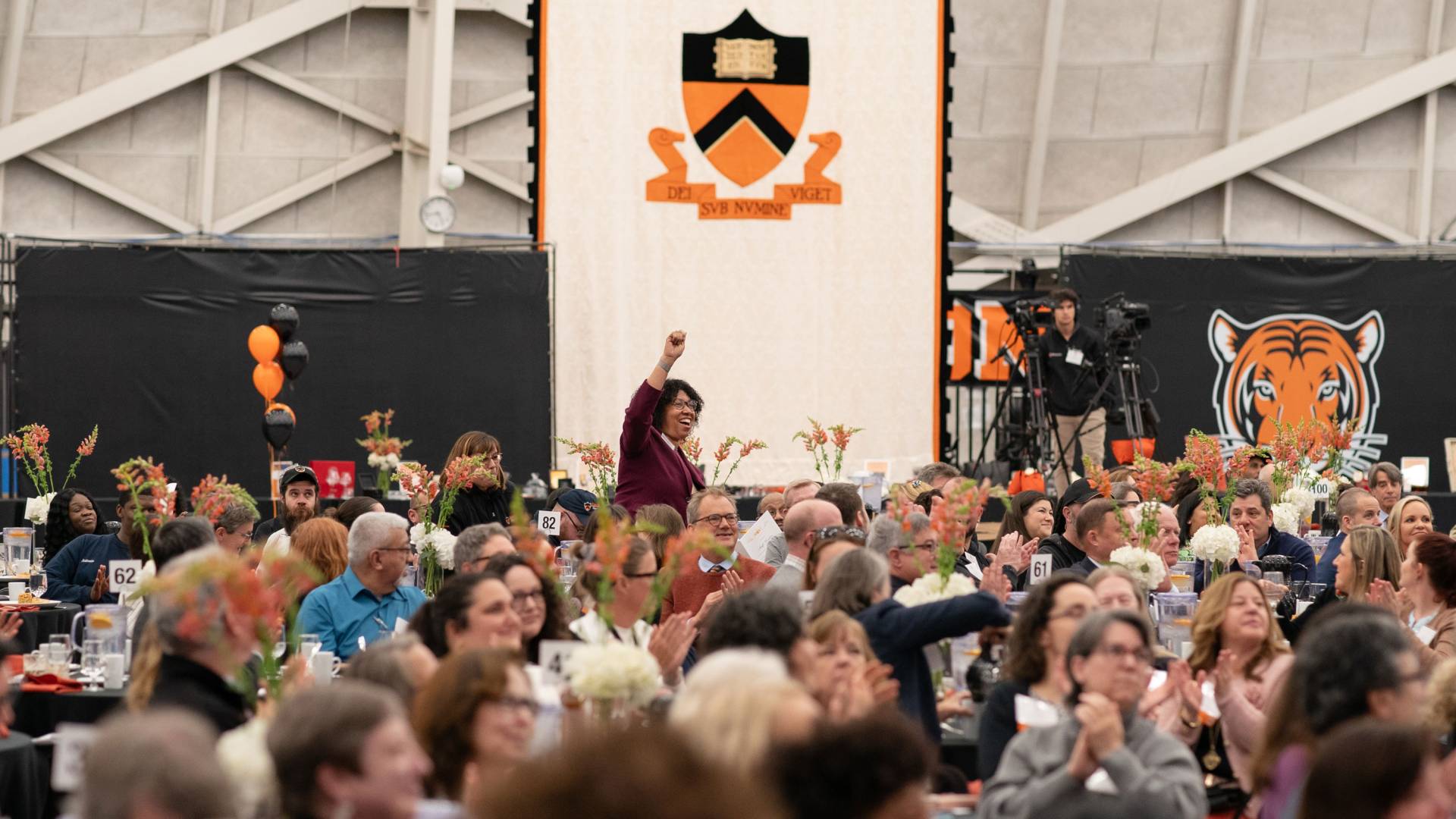 A staff member raises her hand in celebration during the service recognition luncheon