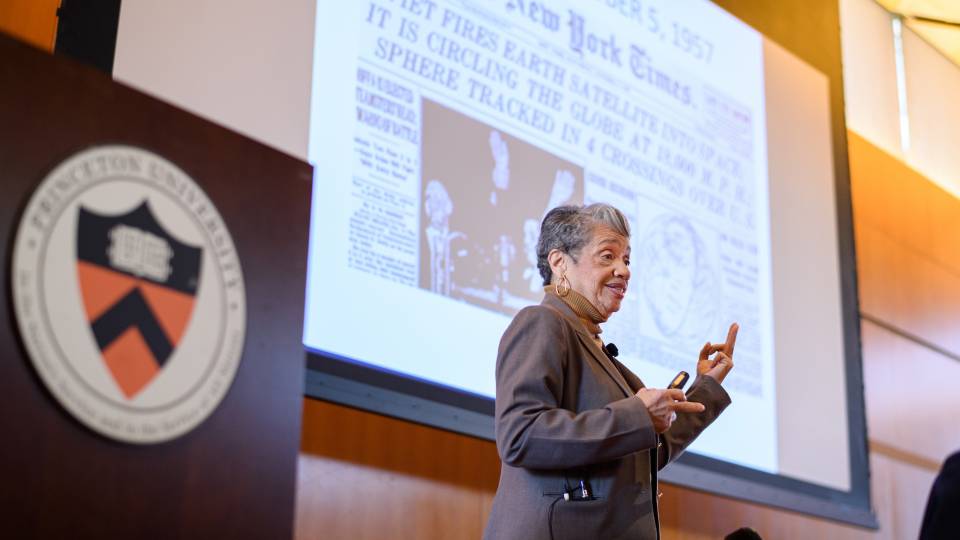 Christine Darden presents a projection of a New York Times 1957 front page that reads, "Soviets fires Earth satellite into space it is circling the globe at 18,000 M.P.H. Sphere tracked in 4 crossings over U.S." 