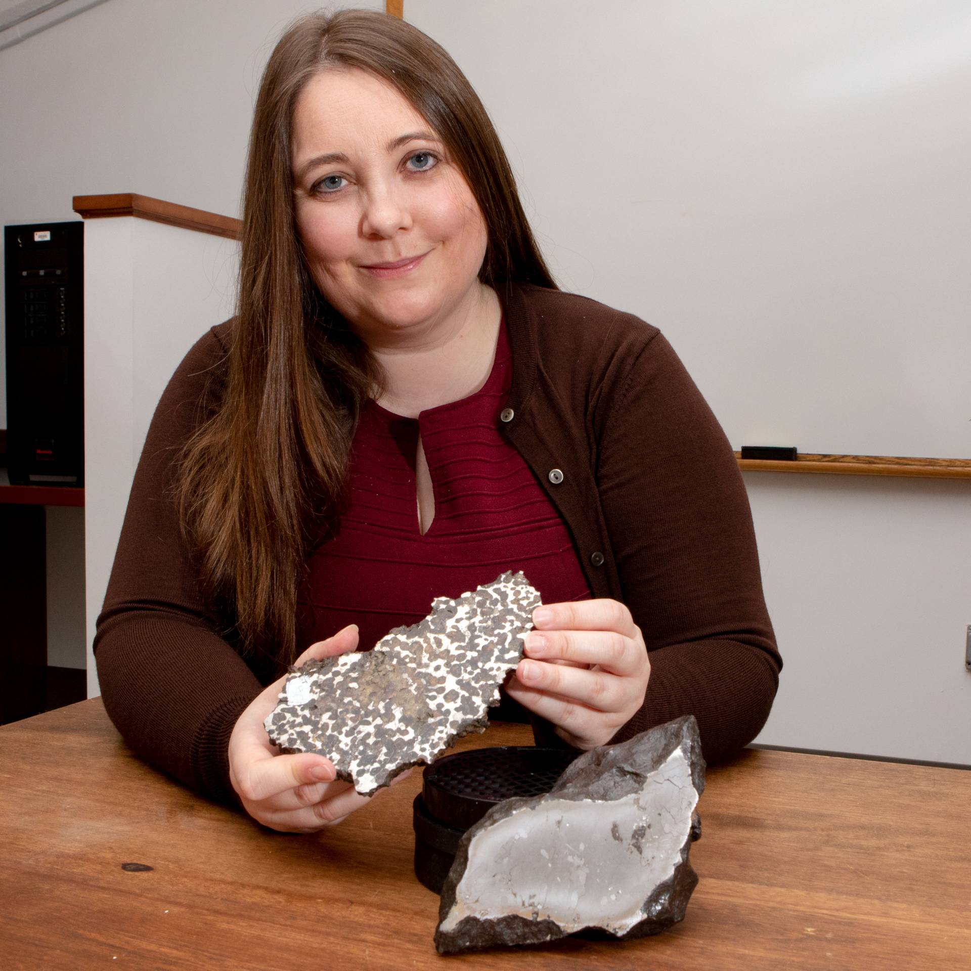 Jessica Irving sits with two meteorites
