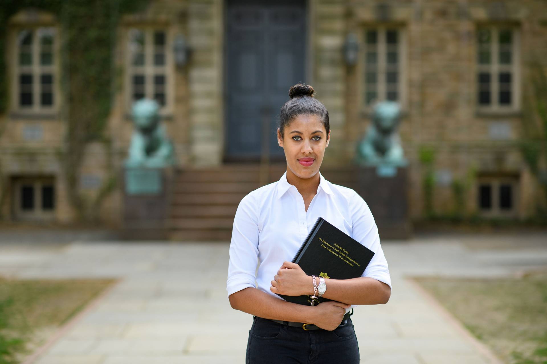 Avanthi Cole holding her senior thesis in front of Nassau Hall