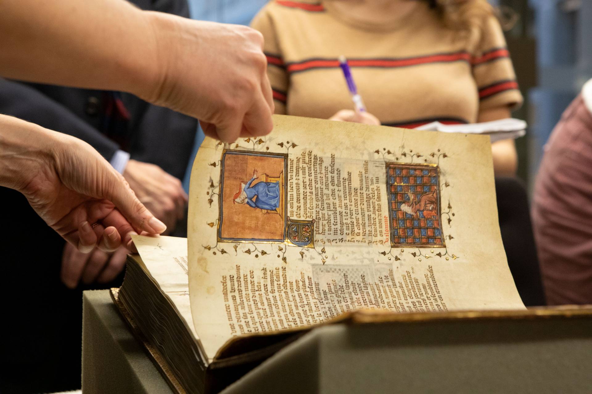Hand turning page of ancient illuminated manuscript