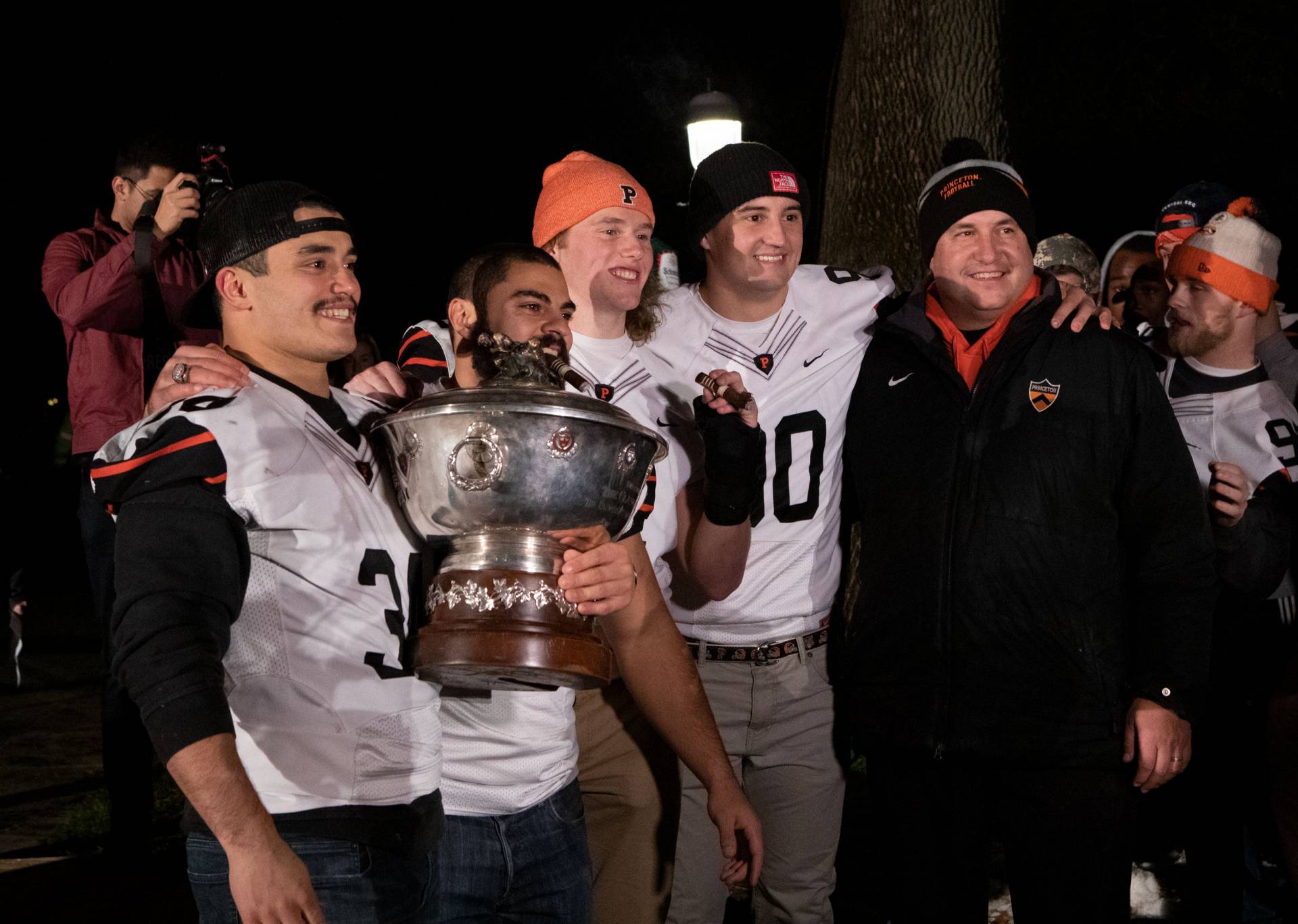 Football team and coach hold the Ivy League championship trophy