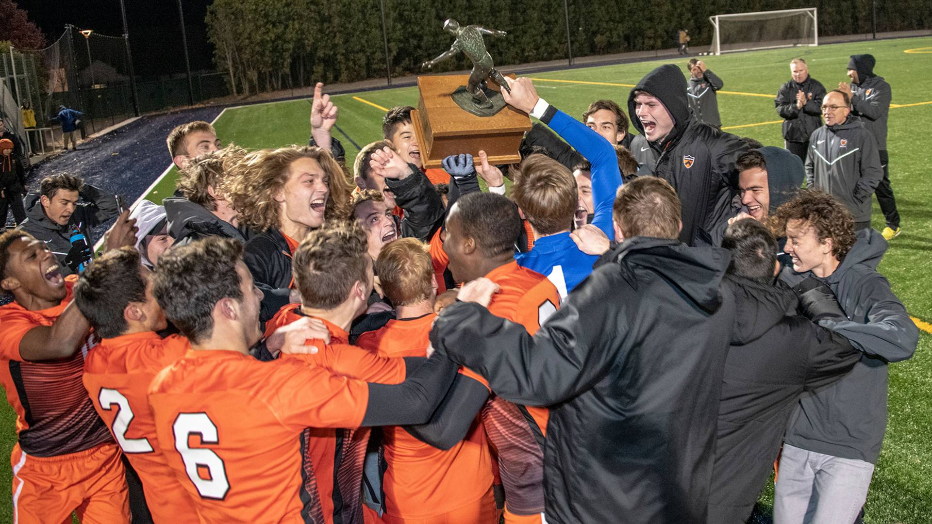 Soccer team celebrates and holds trophy