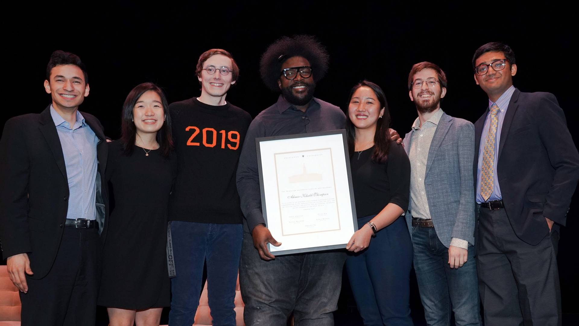 Questlove standing with Princeton seniors holding a certificate for honorary membership of the Class of 2019