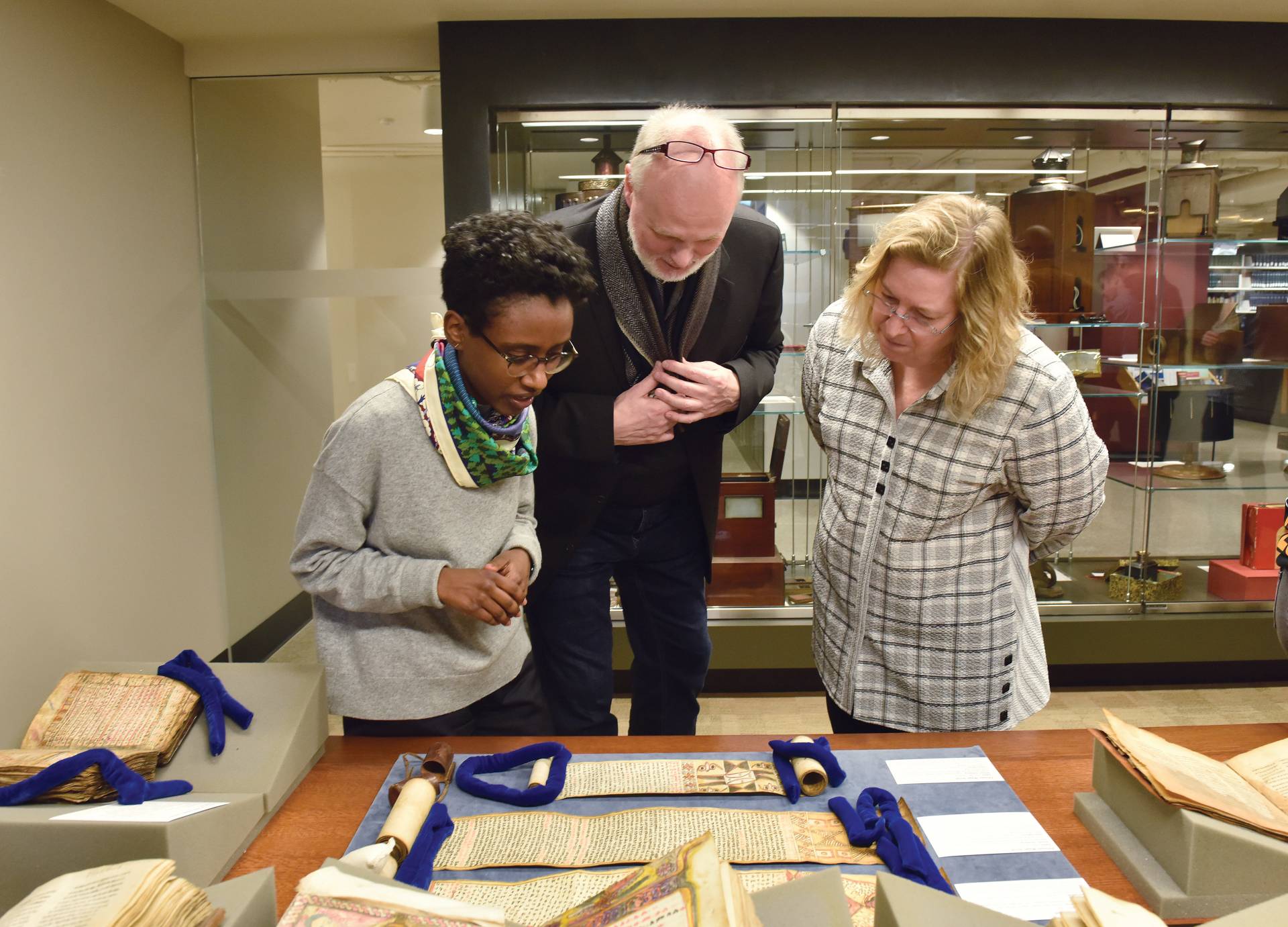 Meseret Oldjira, Michael Kleiner, and Wendy Belcher, looking at and discussing a manuscript on a table display.