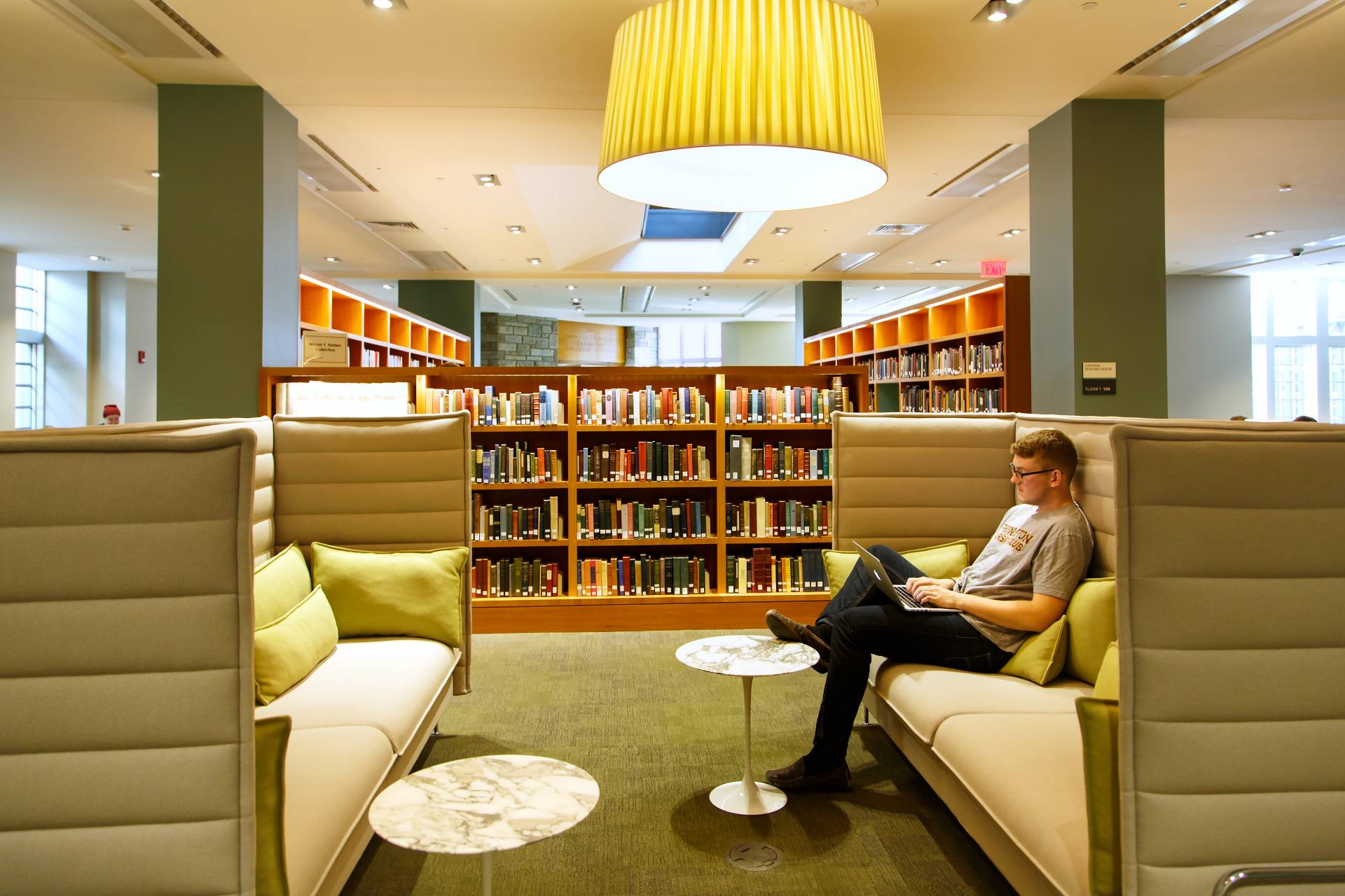 Student sitting on large green couch in library room