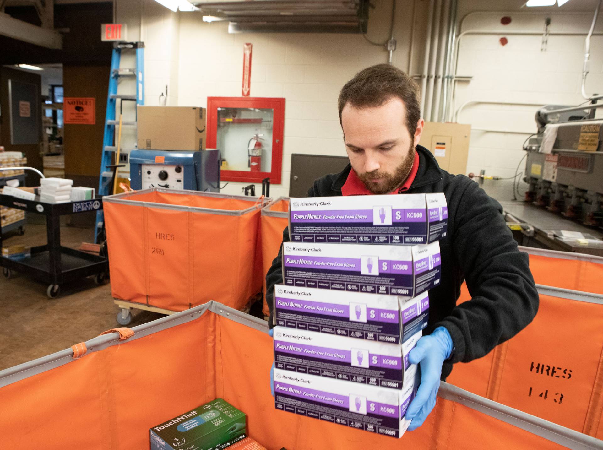 A University staff member loads in a stack of nitrile glove boxes