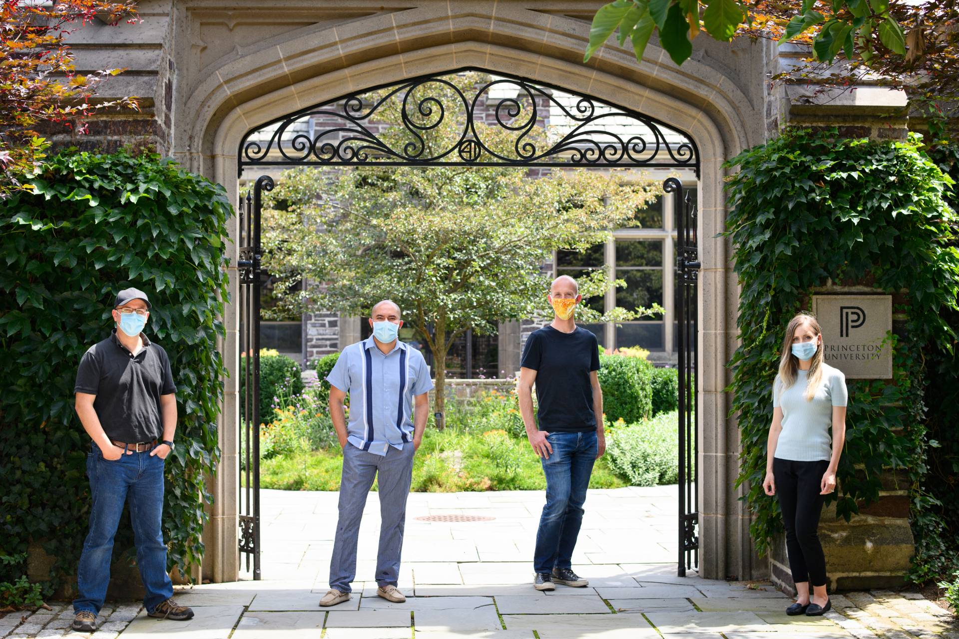 Masked researchers in front of ivy arch