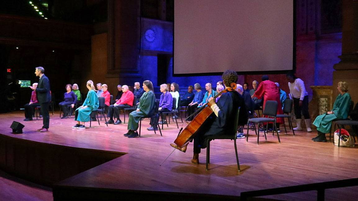 Adults with Parkinson's perform with cellist Joshua Roman on stage in Alexander Hall