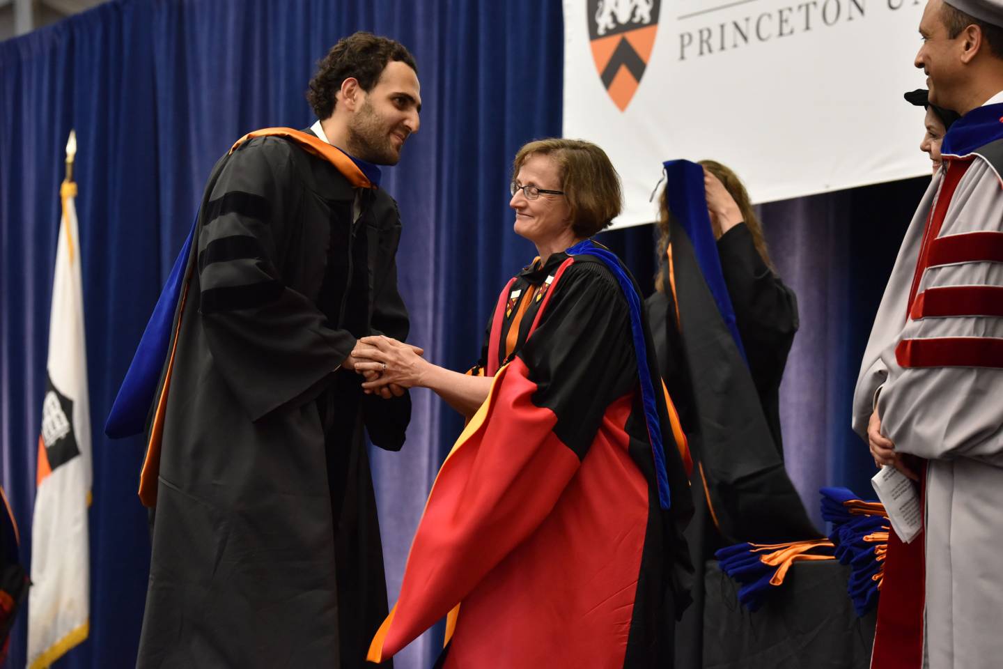 Student shakes hands with advisor at hooding