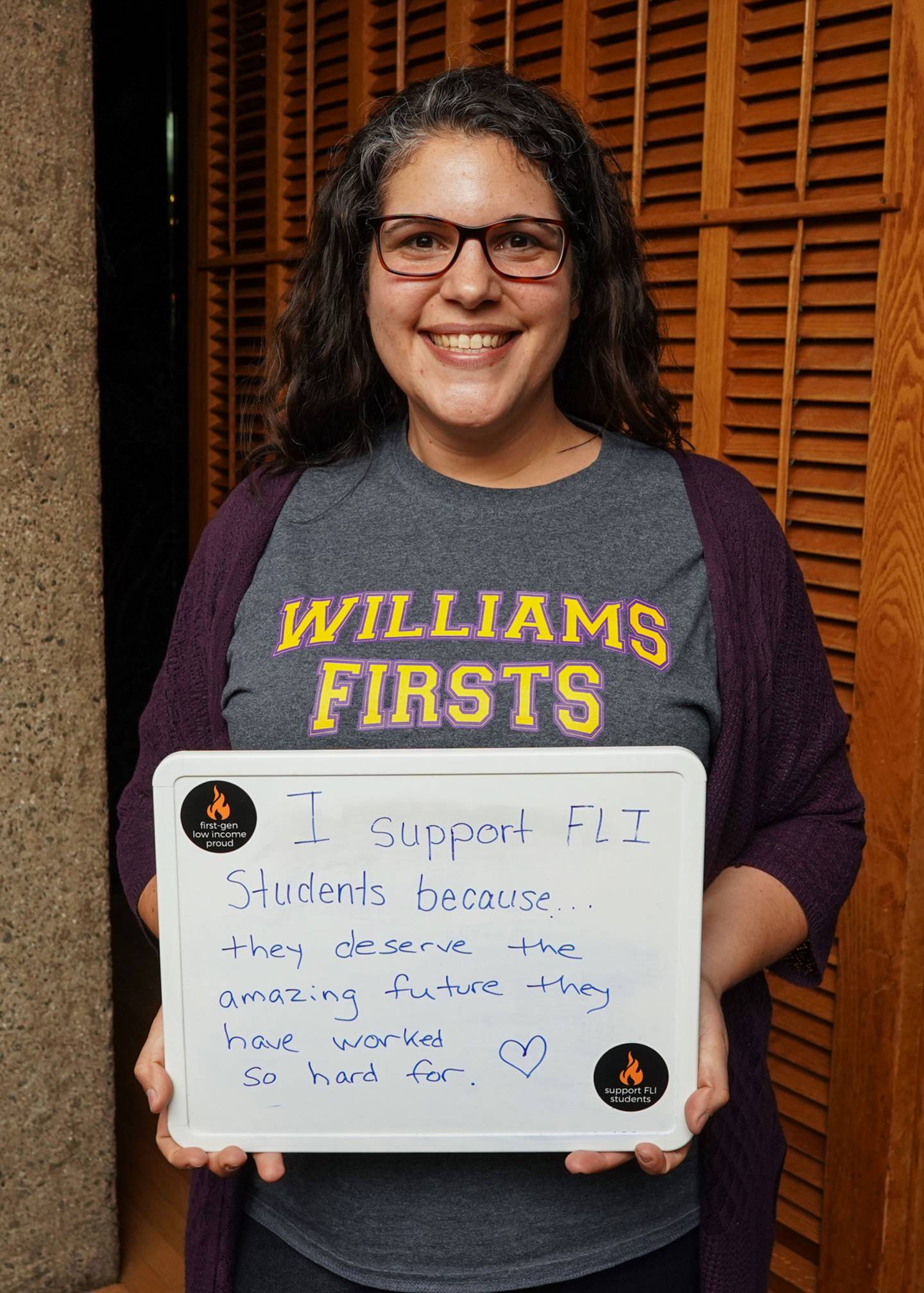April Ruiz holding a whiteboard that says "I support FLI students because they deserve the amazing future they have worked so hard for."