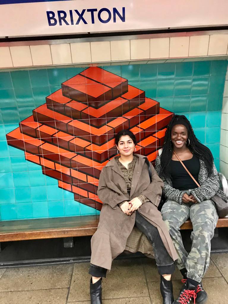 Two women sitting on a bench at a subway station