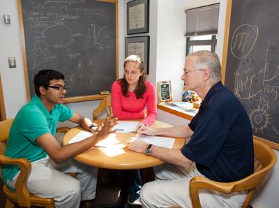 two students and professor sitting at small circular table