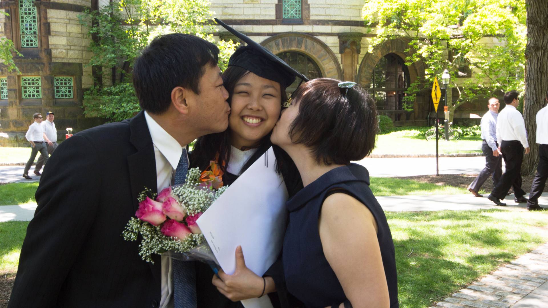 Photo of Parents congratulating their daughter at Commencement with a kiss