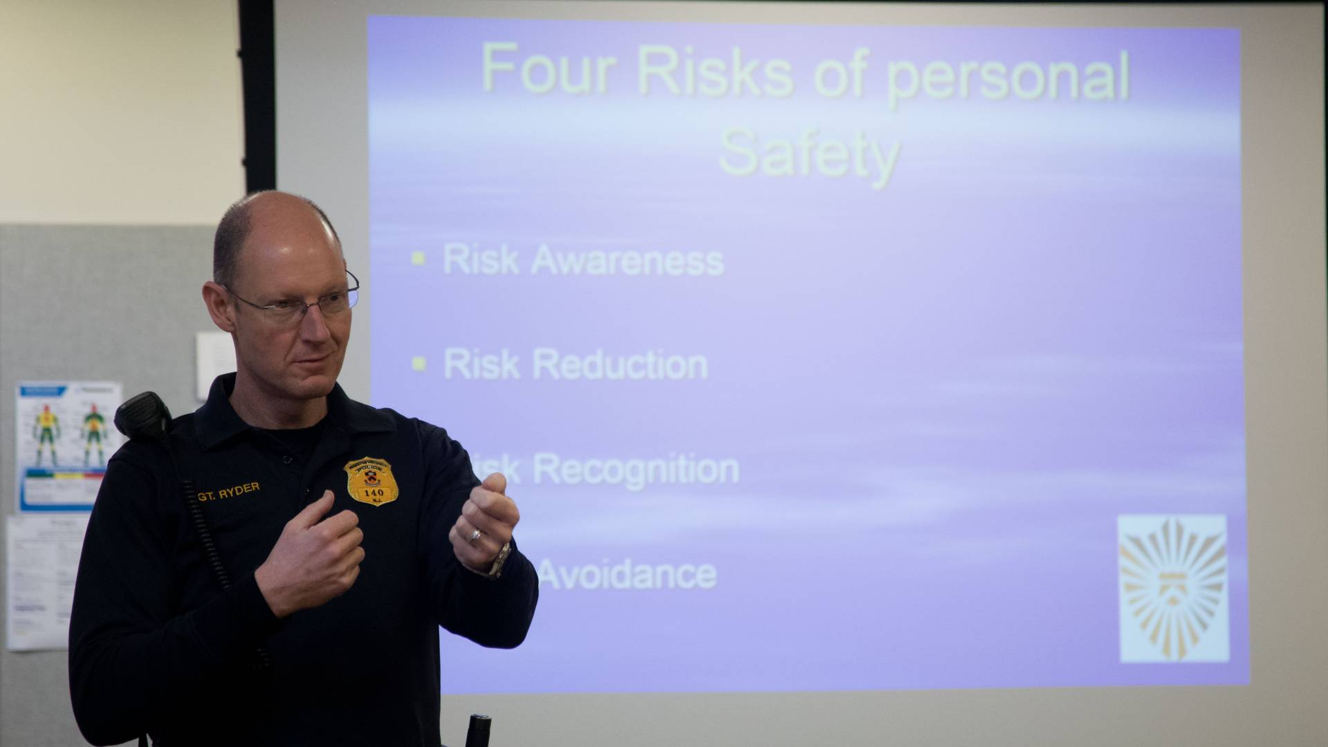Public Safety officer Sean Ryder teaching safety course; Text on Slide: Four Risks of Personal Safety; Risk Awareness; Risk Reduction; Risk Recognition; Risk Avoidance
