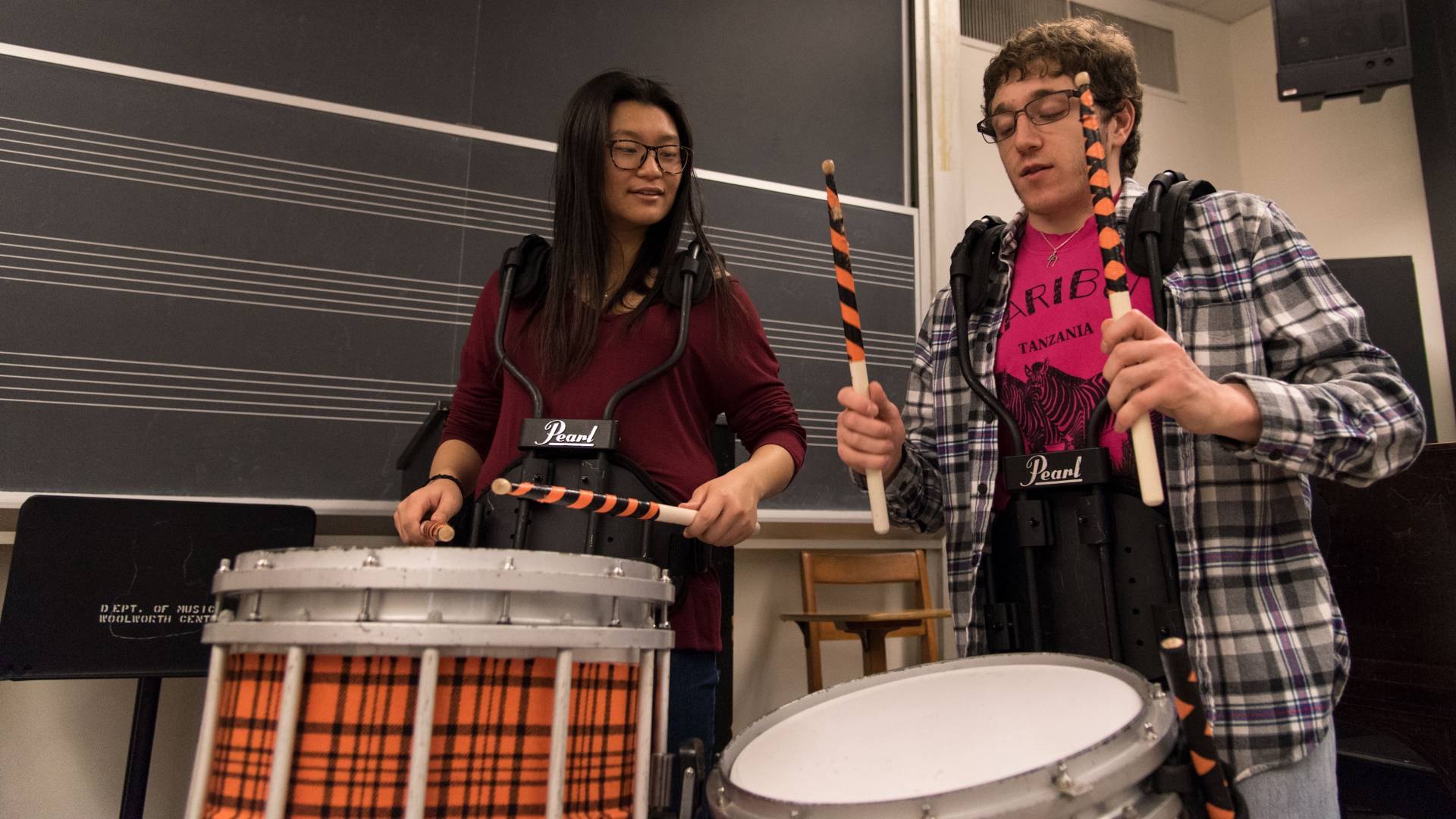 Student demonstrating drums to another student