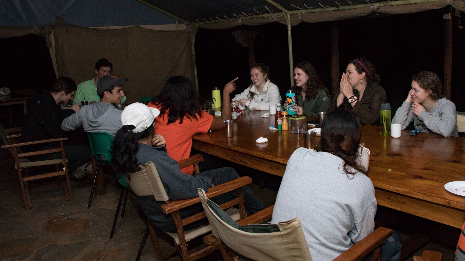 Students eating around a table at night at Mpala