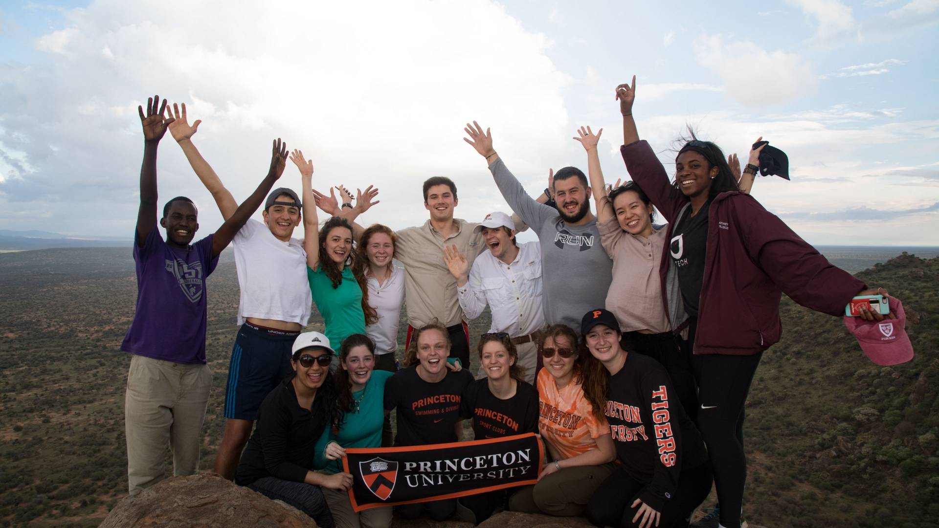 Students standing atop Mt. Mukenya holding Princeton University banner