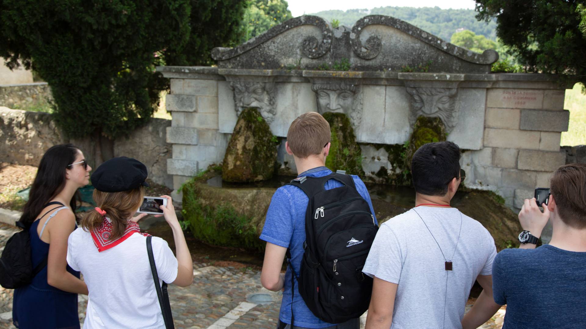 Students looking at fountain with three faced spouts  in France