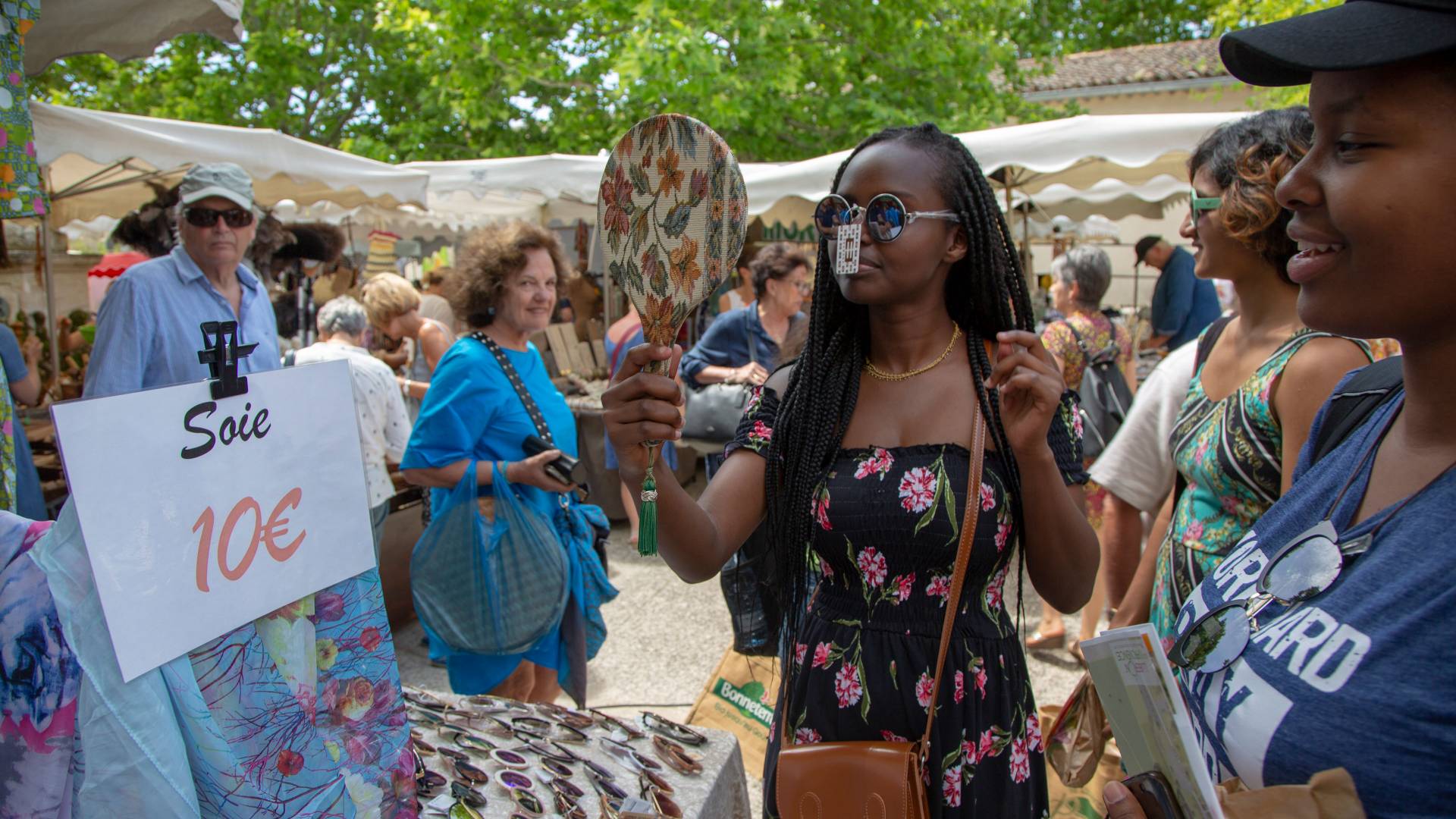 Student trying on sunglasses in outdoor market in France