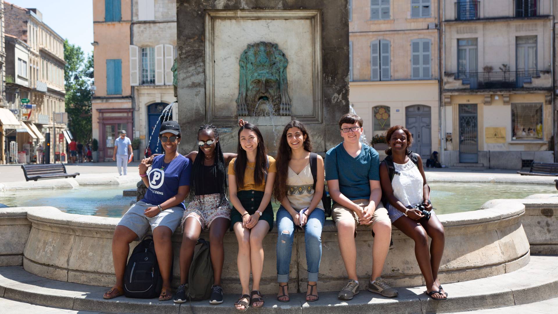 Students sitting at fountain in Arles, France