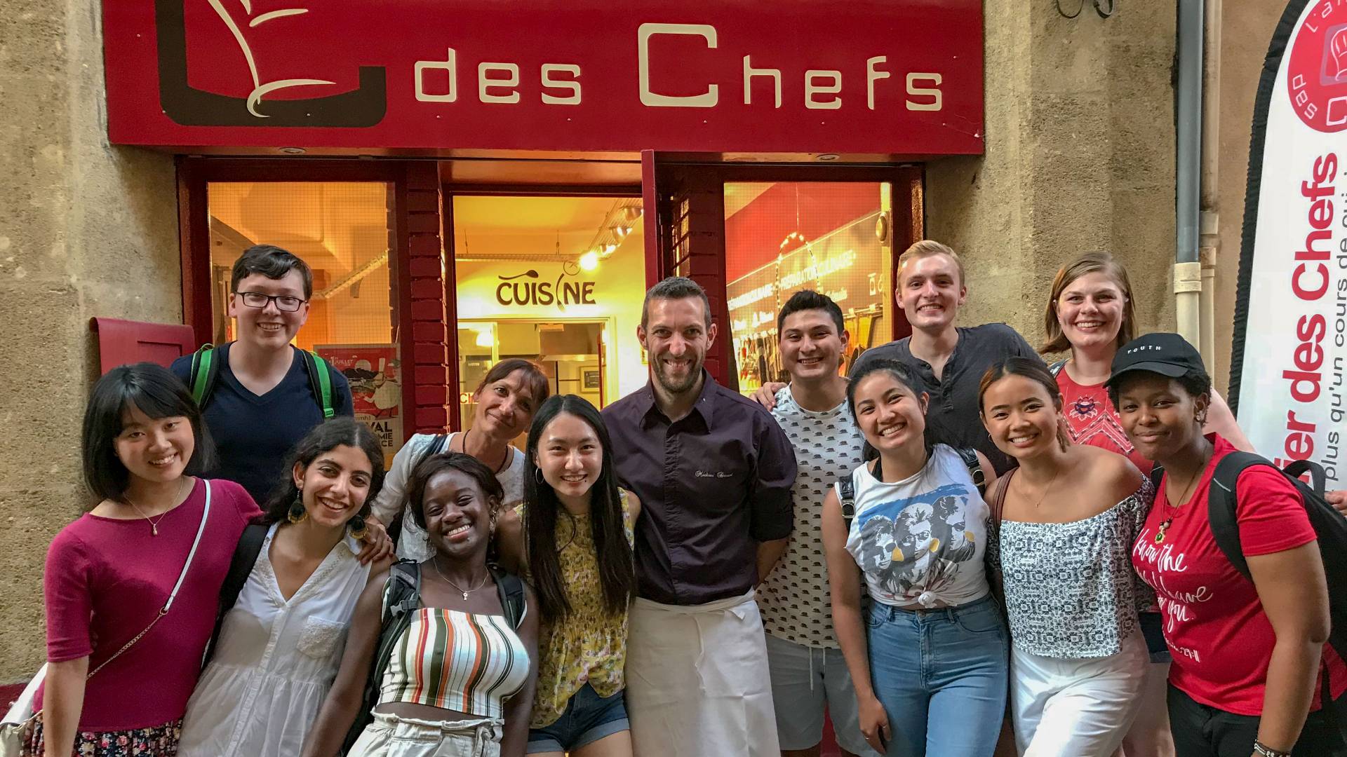Students and chef posing outside cafe in France
