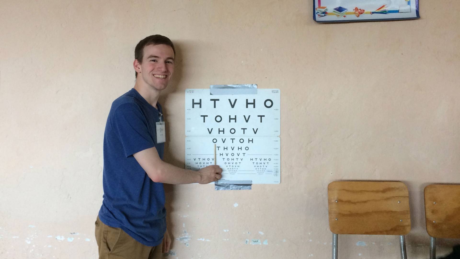 Student pointing to eye chart taped to wall