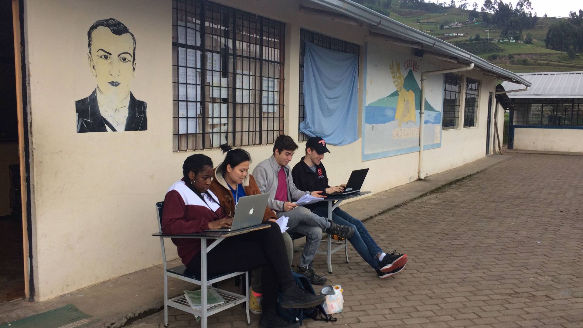 Students working on laptops outside in Ecuador