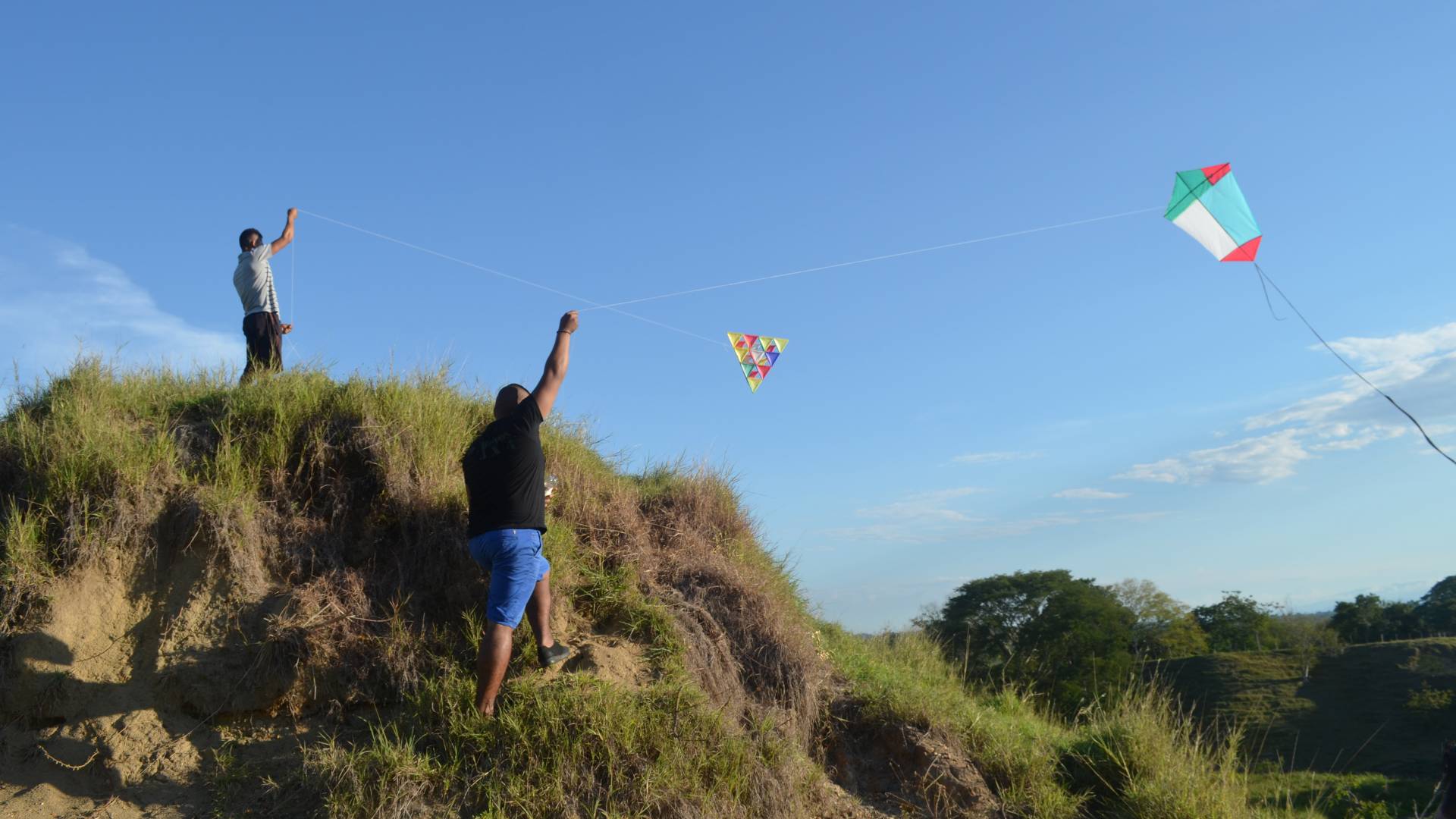 Two men flying kites on hill top