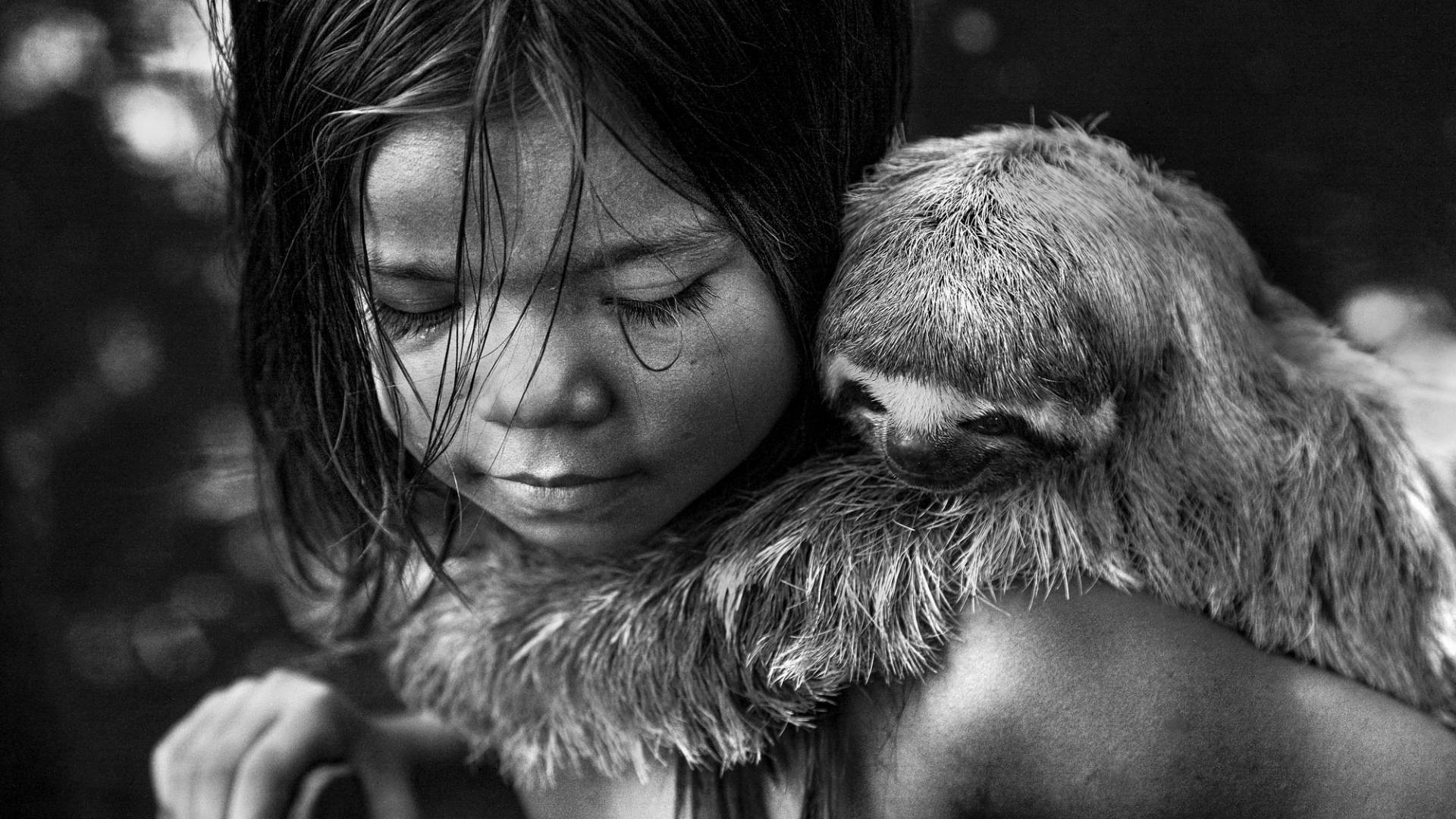 A young girl with a sloth holding onto her back