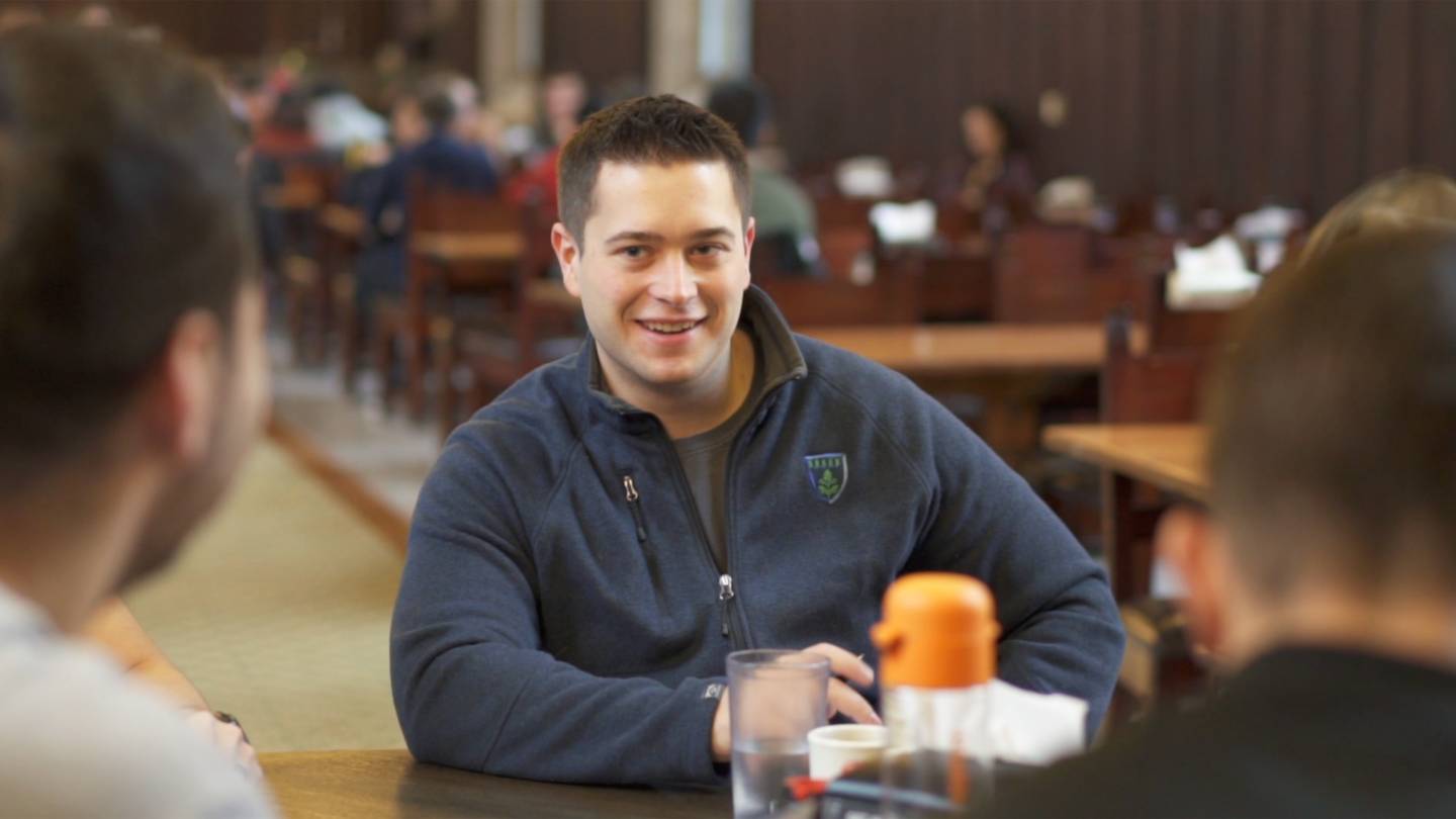 Tyler Eddy sitting a table in a dining Hall with friends