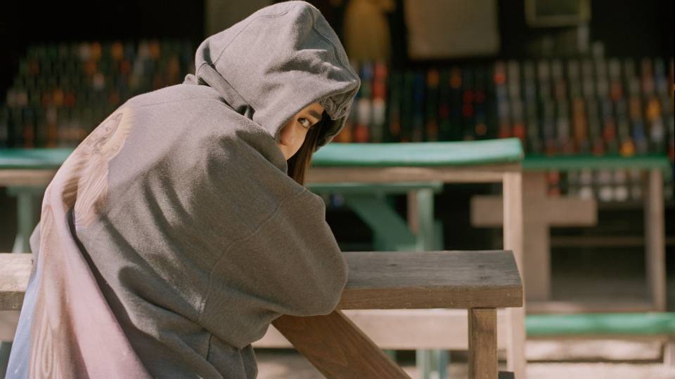 Student in hooded sweatshirt looking back at camera