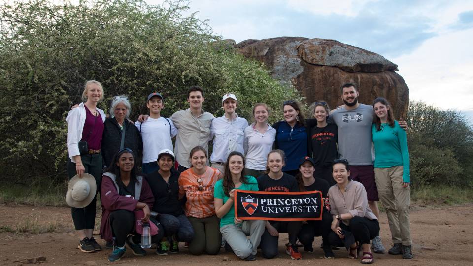Students, faculty and researchers standing at base of Mt. Mukenya holding Princeton University banner