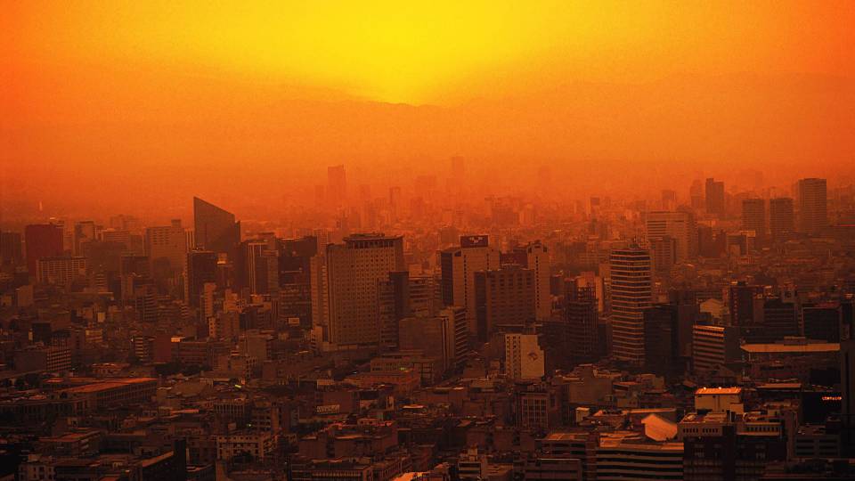Orange tinted image of a city with sun and heat over it