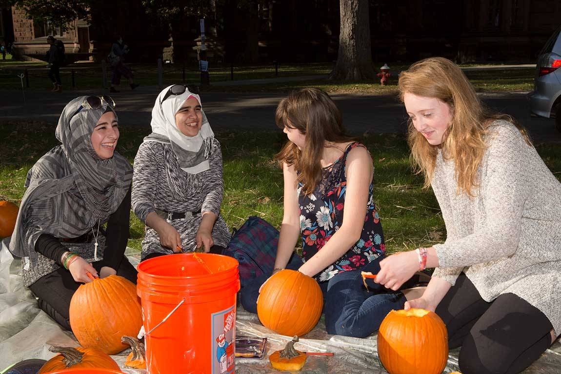  From left to right: Syrian refugees Rahaf and Reem get to know Princeton sophomores Stephanie Ward and Lilly Chadwick as they carve pumpkins on the lawn in front of Murray Dodge Hall.