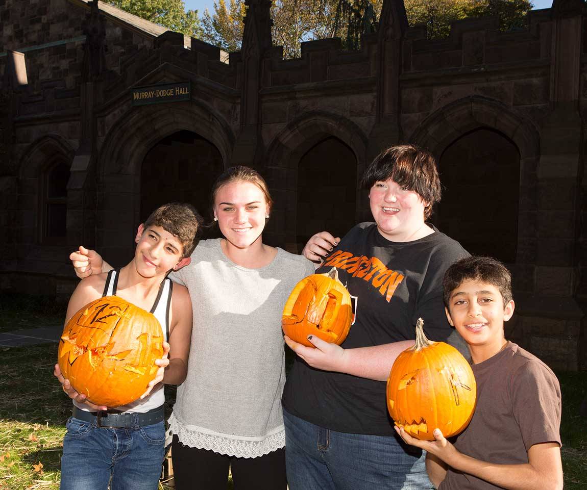 Princeton sophomores Carly Bonnet (center left) and Téa Wimer (center right) show off the pumpkins they carved with Abdulhafiz (far left) and Khaled (far right).