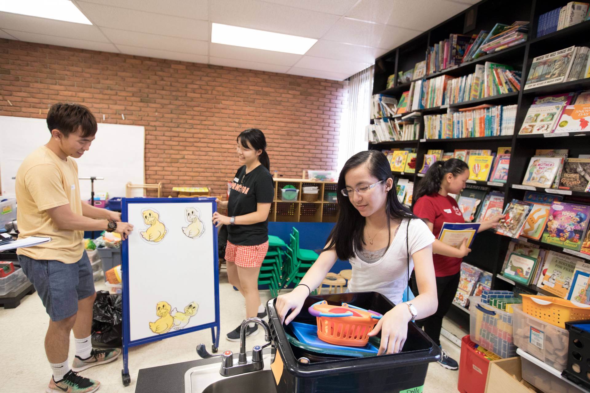 Students cleaning YWCA storeroom of books and toys