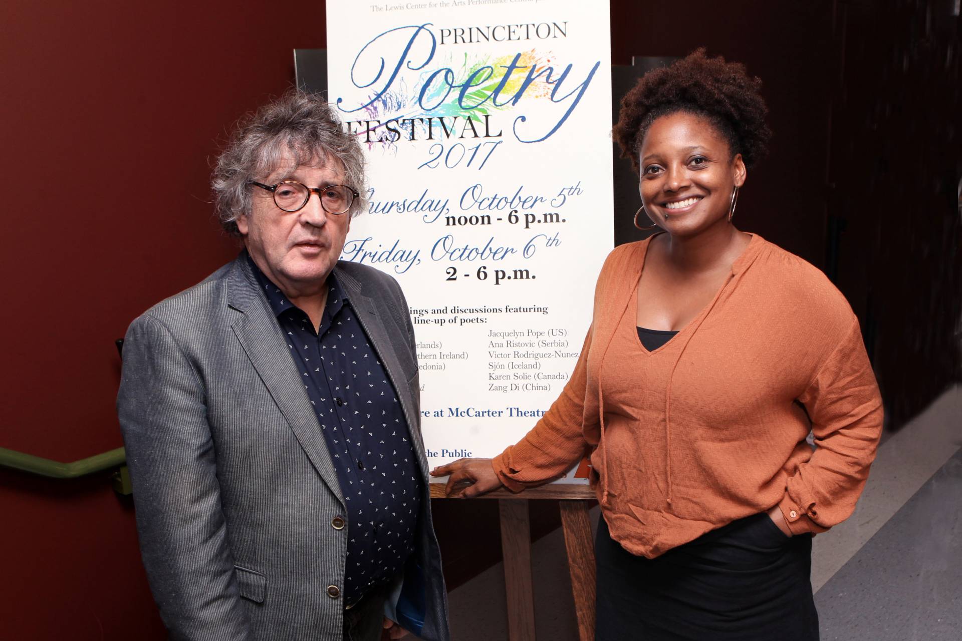 Paul Muldoon and Tracy Smith stand by Poetry Festival poster