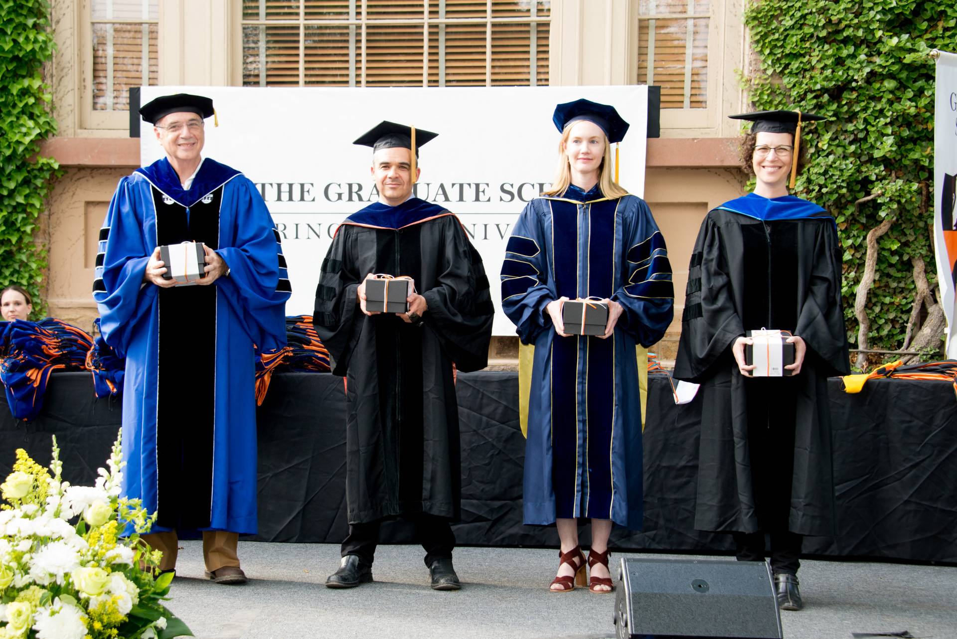 Graduate Mentoring Awards recipients at Hooding Ceremony stand together on stage