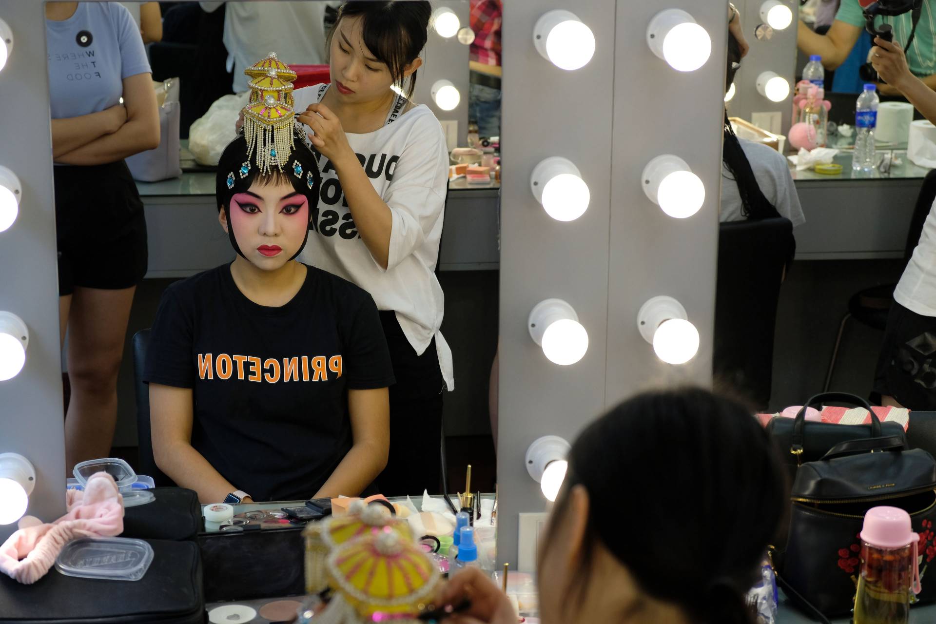 Reflection in mirror of student having makeup applied