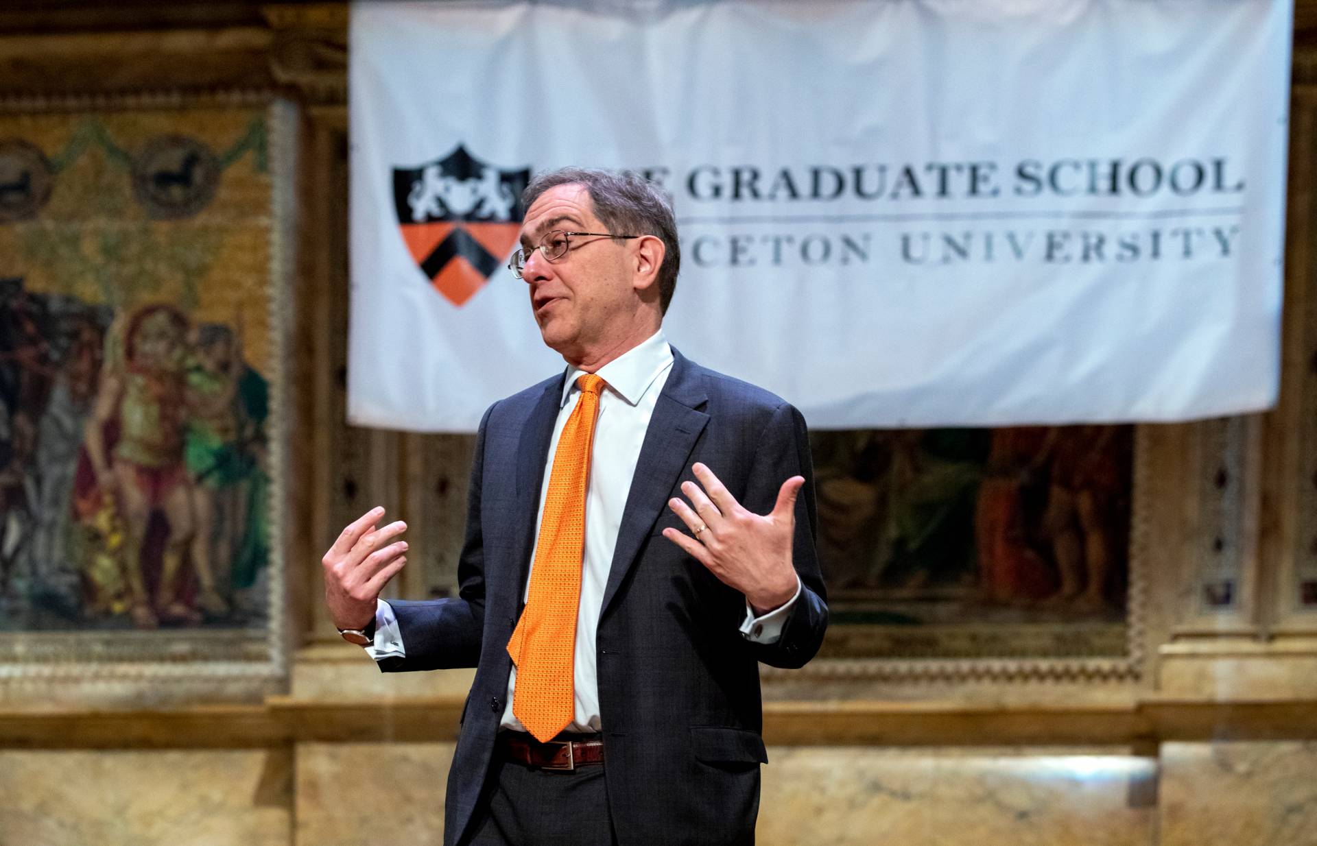 Christopher Eisgruber standing speaking in front of the Graduate School banner