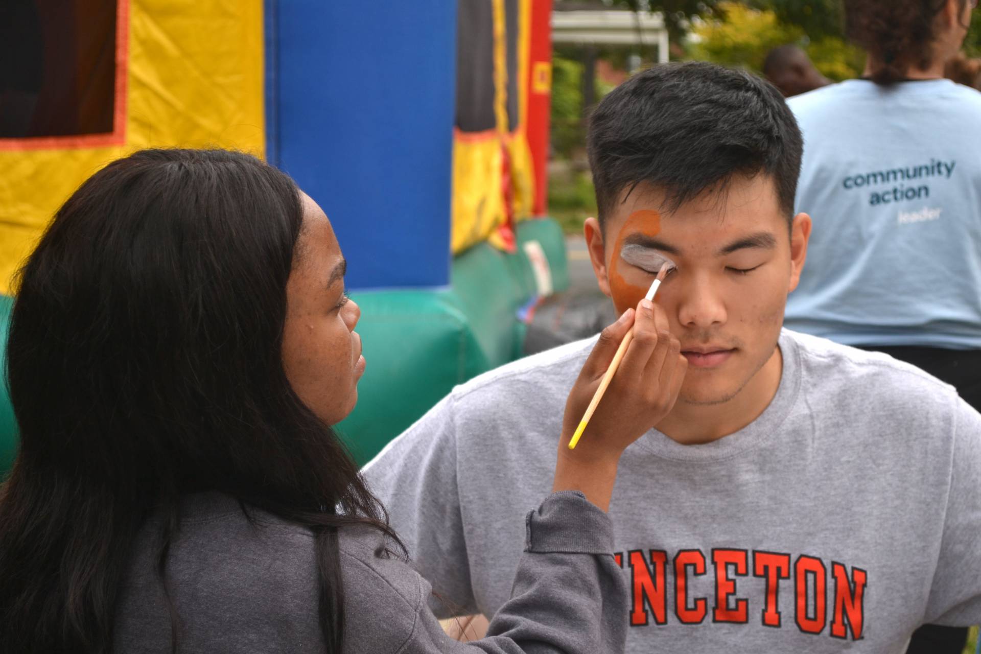 A student applies face paint on another student