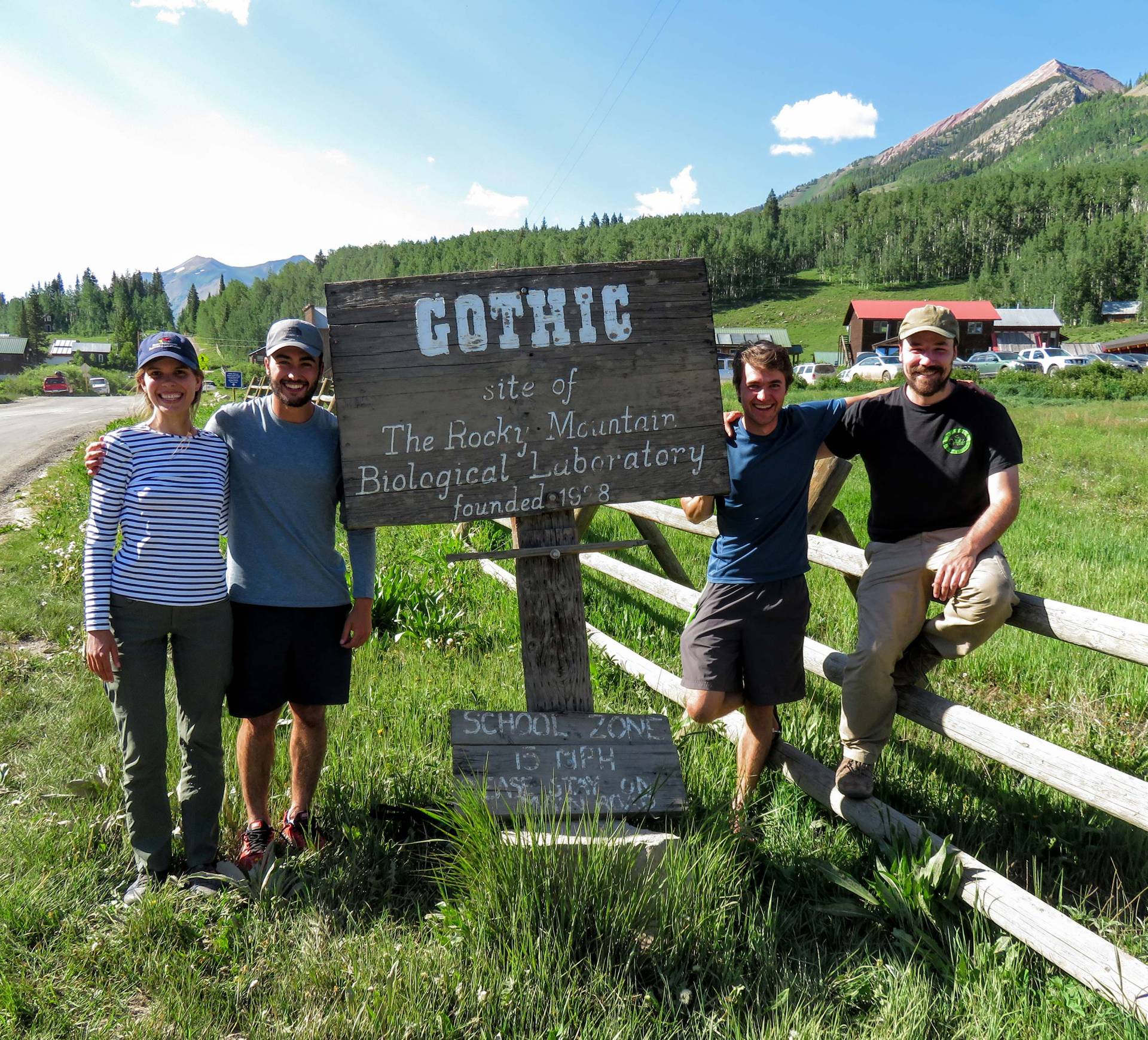 four researchers stand next to a sign at Rocky Mountain Biological Laboratory