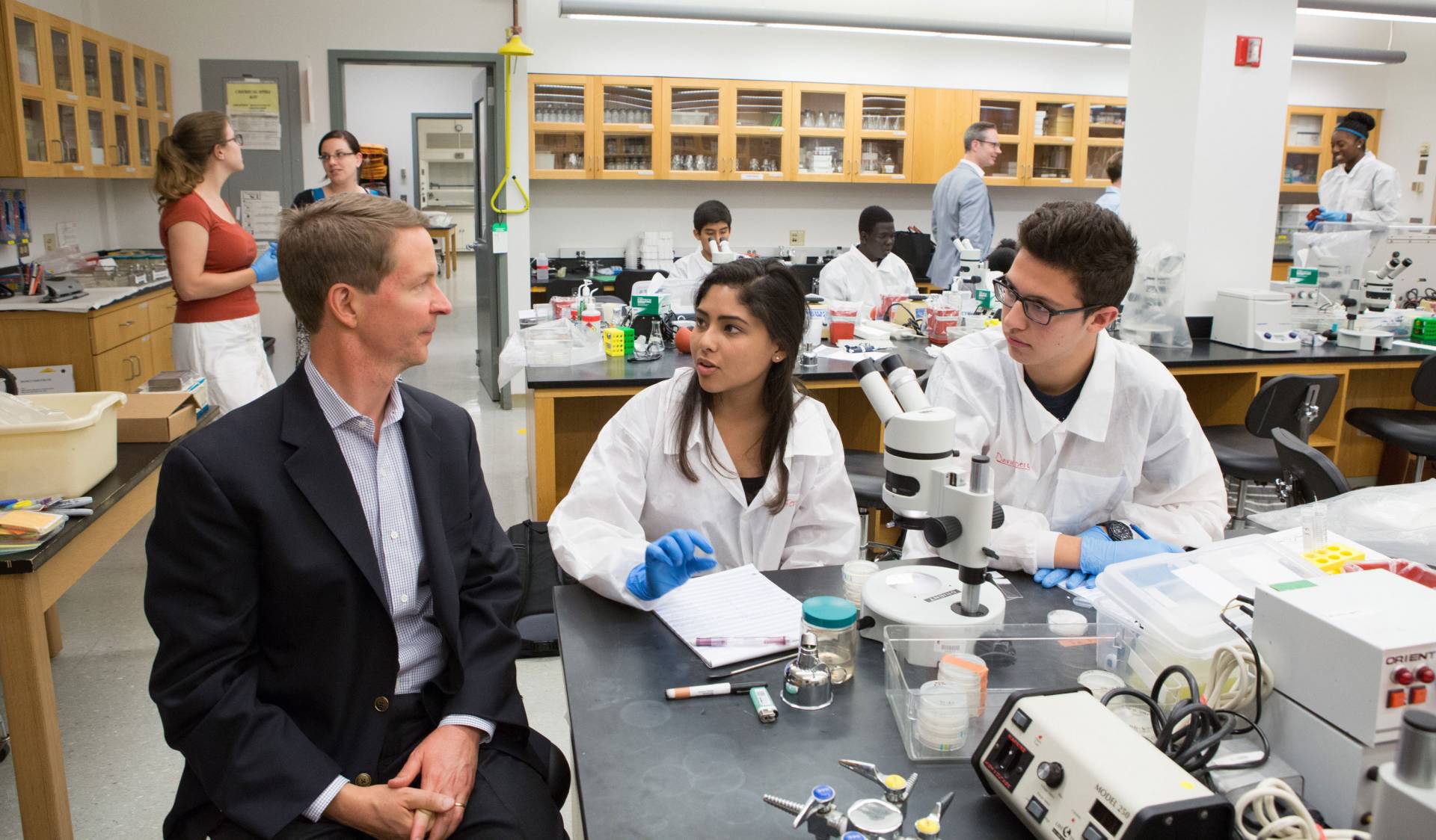 Bob Peck speaks to students while in a laboratory