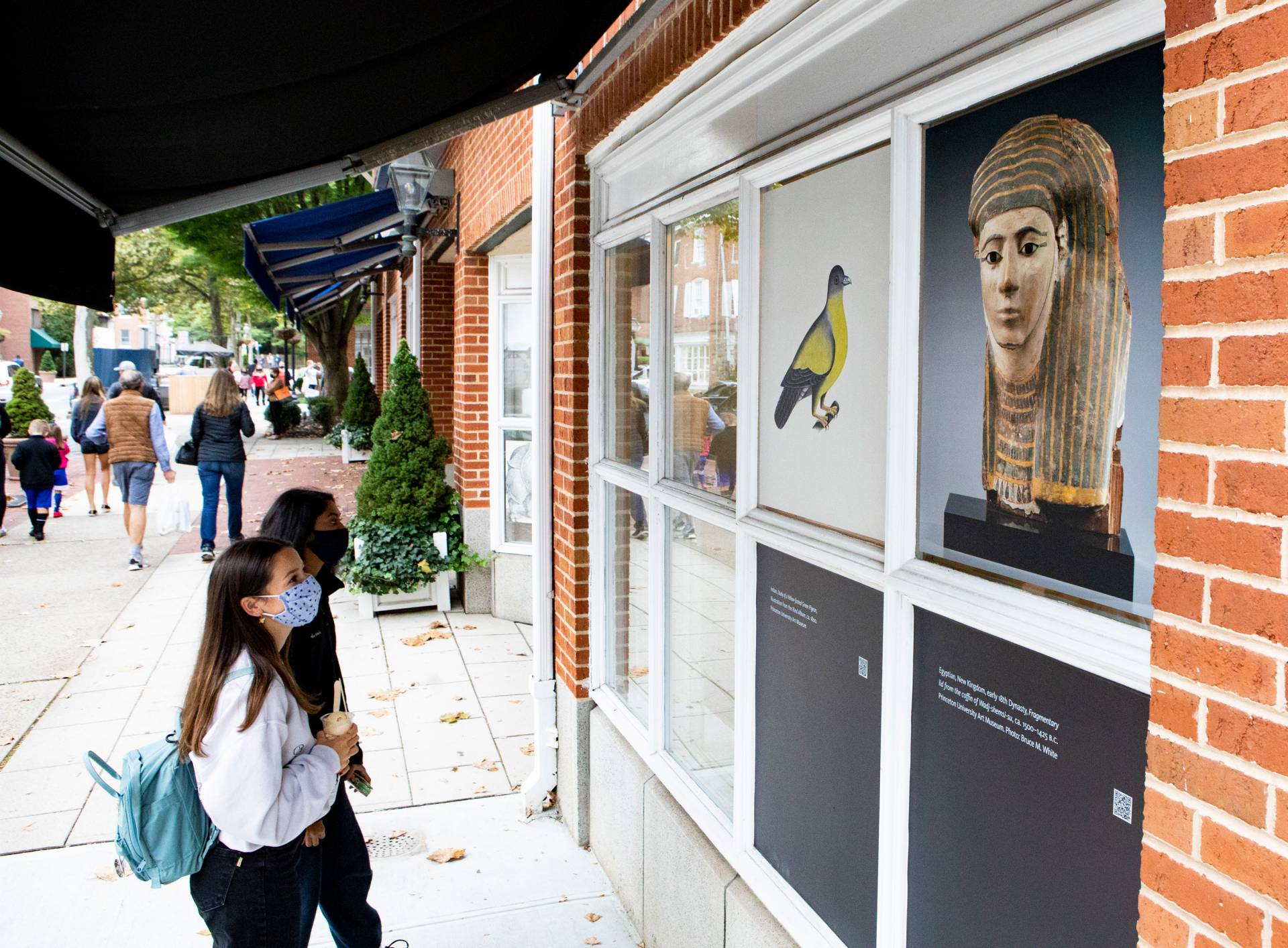 passers-by stop to look at art in shop windows