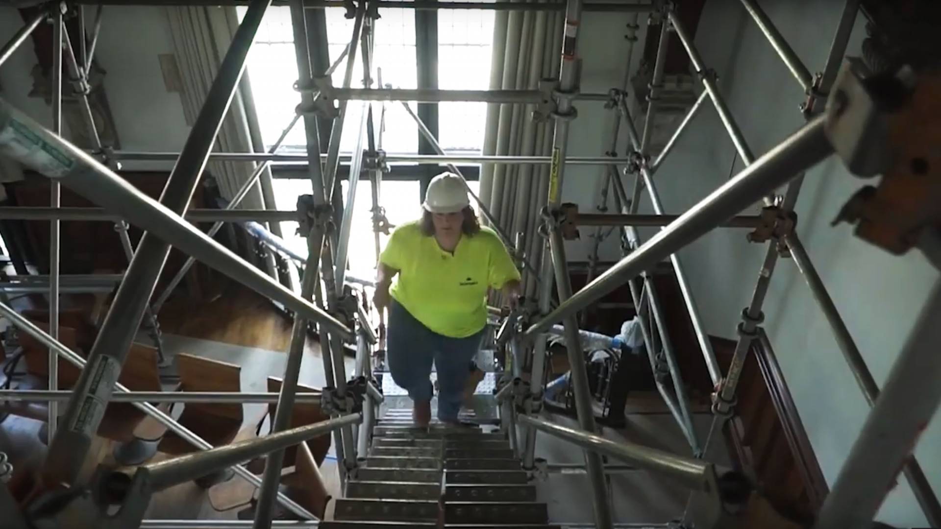 Owner of Golden Crown Contractors walks up the scaffolding stairs at McCosh auditorium