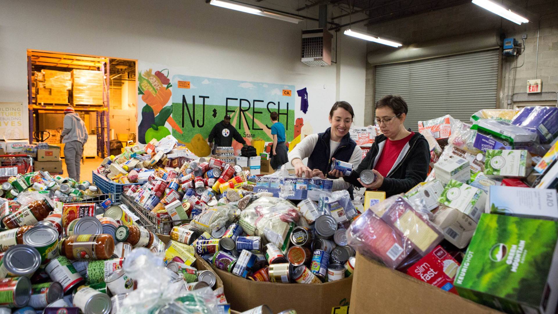 Two volunteers sort canned food donations at the Mercer Street food bank