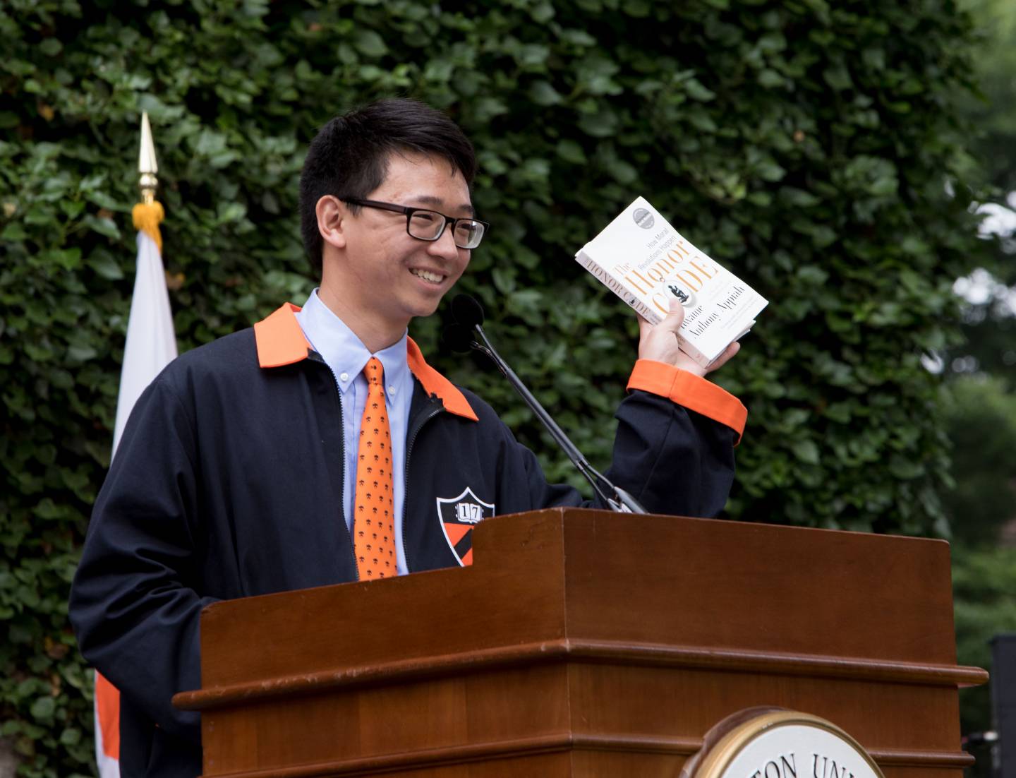 Class president at podium holding book during Class Day 2017 ceremony